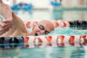 senior man swimming laps in pool